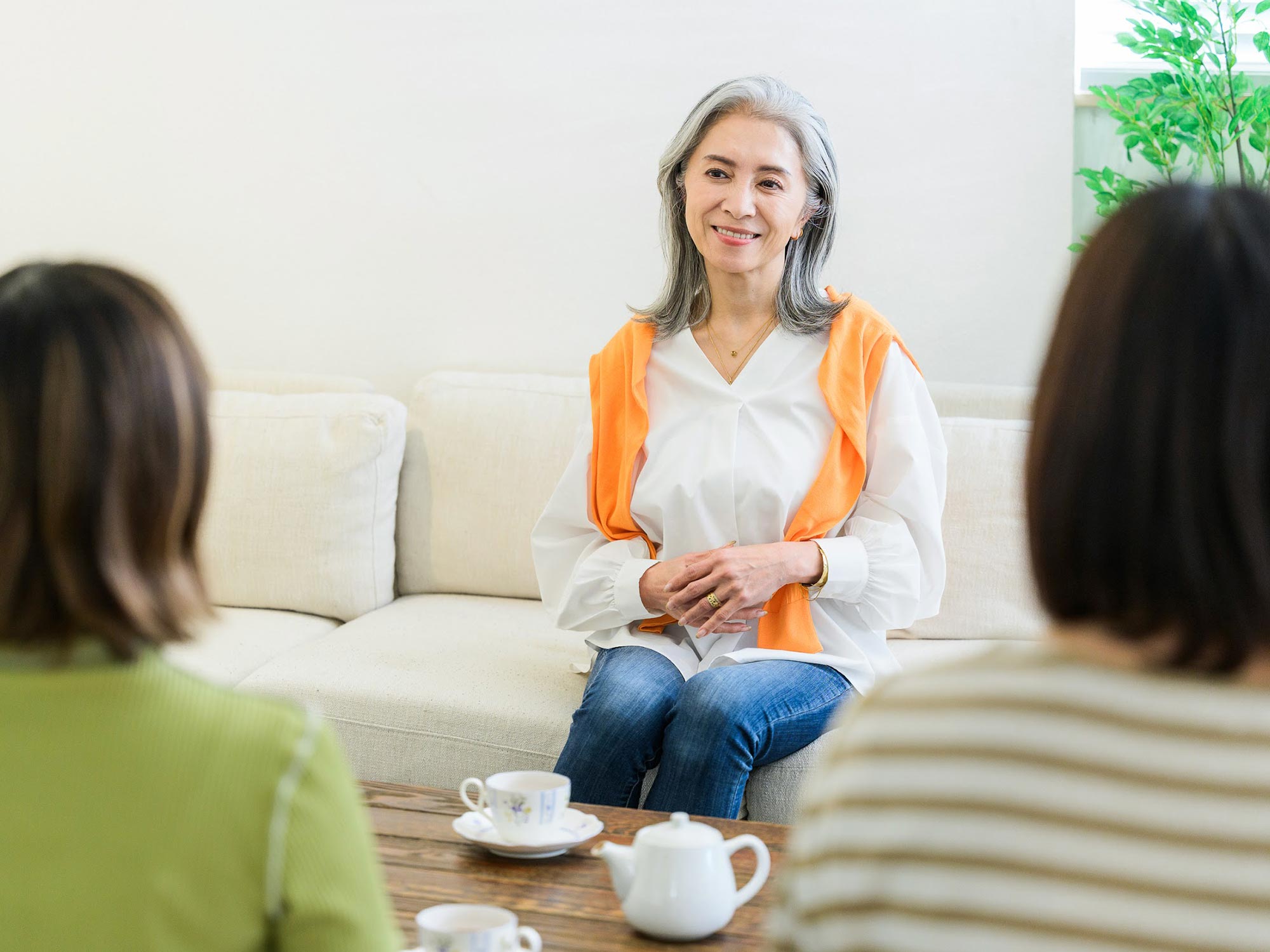 ソファのあるリビングで女性三人が会話をしている写真